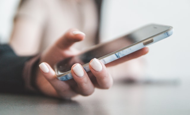 person with pink nails holding a cellphone